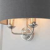 Brenley 2 Light Wall Light in nickel finish with grey fabric drum shade, twin candle-style arms on a ridged circular backplate.