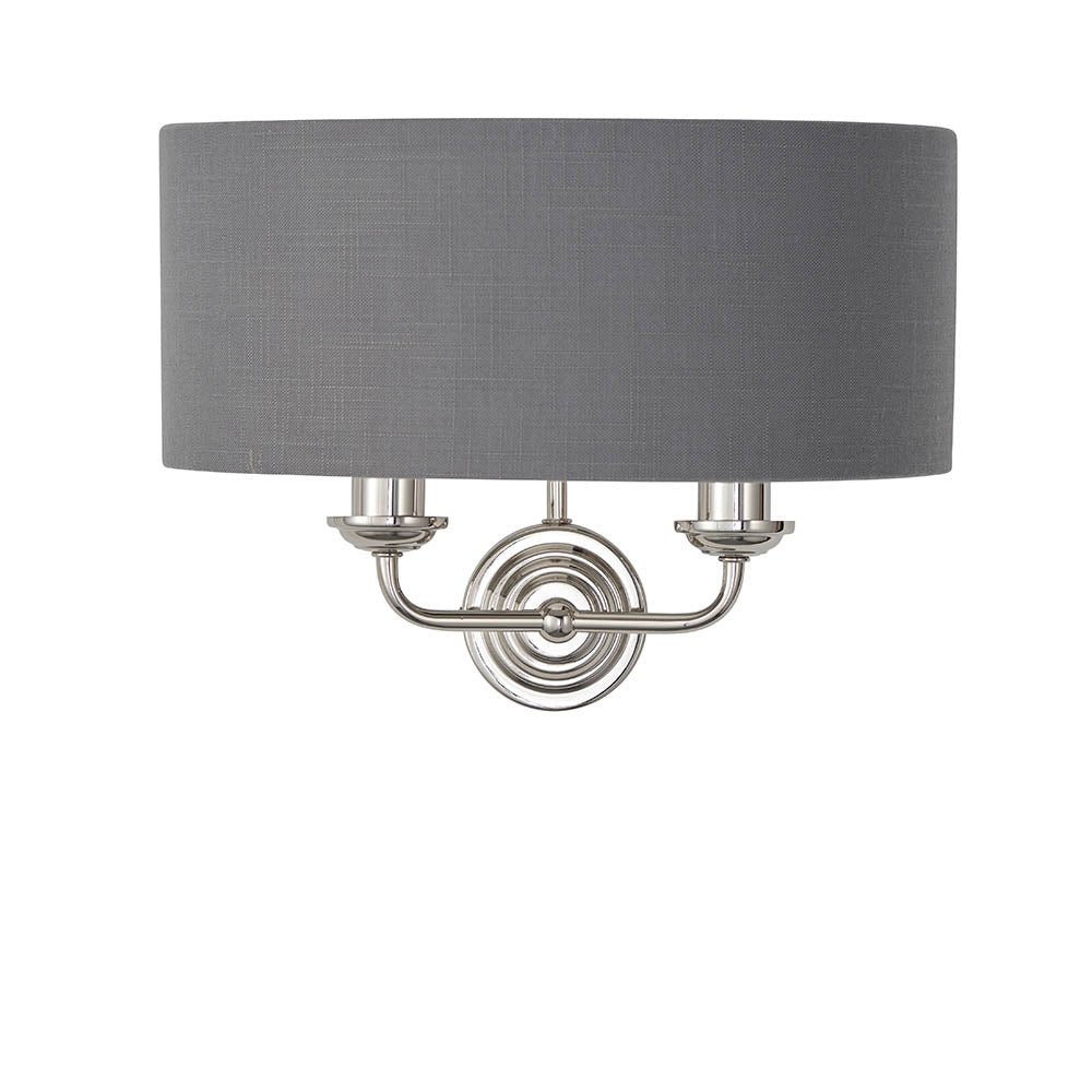 Brenley 2 Light Wall Light in nickel with a grey fabric drum shade and twin candle-style arms on a round backplate, plain white background.