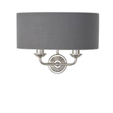 Brenley 2 Light Wall Light in nickel with a grey fabric drum shade and twin candle-style arms on a round backplate, plain white background.
