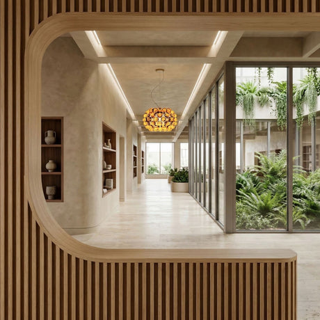 A modern interior features wood paneling, built-in shelves with ceramics, large windows, and an indoor garden. The Briller LED Small Pendant Light in gold adds elegance as natural light brightens the minimalist, open space.
