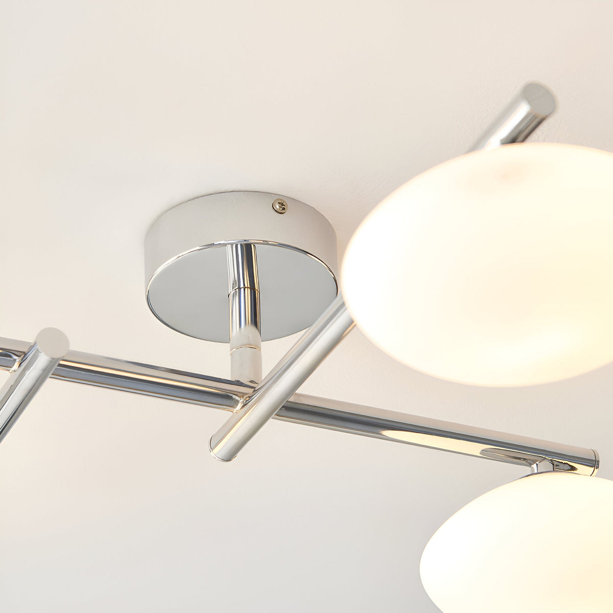 Close-up of the Denby 4-light semi-flush bathroom ceiling light in chrome, showing the circular ceiling plate, angled arms, and opal glass globe shades.