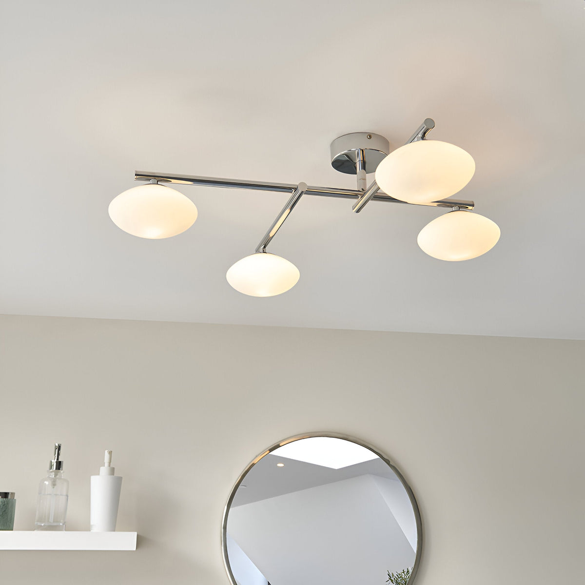 Denby 4 Light Semi-Flush Bathroom Ceiling Light in chrome with white oval glass shades on angled arms, shown installed above a round mirror.