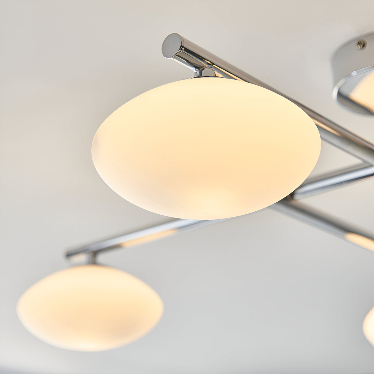 Denby 4 Light Semi-Flush Bathroom Ceiling Light in chrome, close-up of oval opal glass shades on angled chrome arms against a light ceiling.