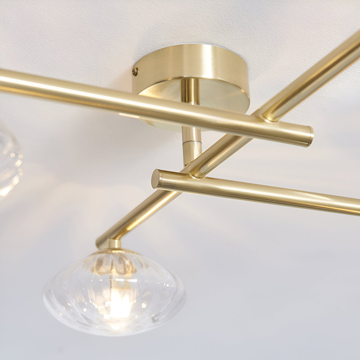 Denby 4 Light Semi-Flush Bathroom Ceiling Light in brass, close-up of angled arms and circular ceiling plate with a clear ribbed glass shade below.