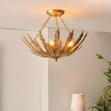 Endon Colette 3 light flush ceiling light in gold, with layered metal fern leaves fanning around three E14 lamps, installed on a neutral ceiling.