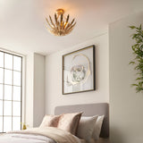 Endon Colette 3 light flush ceiling light in gold with layered metal leaf design, installed in a bedroom above a grey headboard and framed artwork.