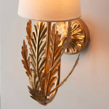 Colette Wall Light in gold leaf finish with layered leaf detail and cream fabric shade, mounted on a round backplate against a plain wall.