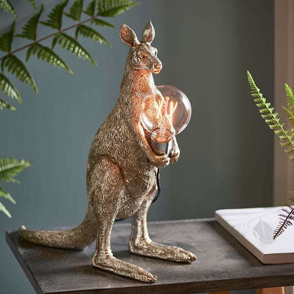 Endon Brockgrove Kangaroo table lamp in vintage silver resin, holding an exposed E27 filament bulb in a chrome holder, on a dark console with ferns.