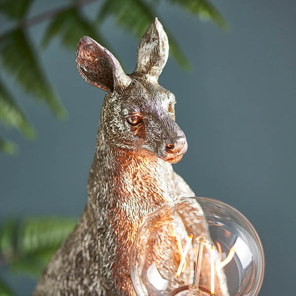 Endon Brockgrove kangaroo table lamp in vintage silver resin, close-up of the figurine's head and exposed E27 filament bulb against a dark backdrop.