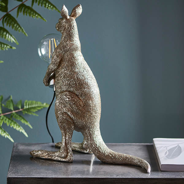 Endon Brockgrove Kangaroo table lamp in vintage silver resin with exposed E27 filament bulb and chrome holder, styled on a dark console with ferns.