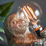 Close-up of the Endon Cliffmont table lamp showing the vintage silver resin sloth holding an exposed E27 filament bulb in a chrome lamp holder.