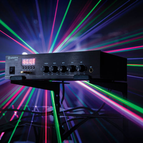 Adastra DM60 mixer-amp with digital display, control knobs, and USB port, shown black casing on a stand amid colourful laser light streaks.