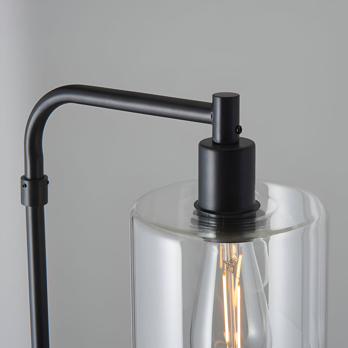 Close-up of the Cranmere Floor Lamp in matt black, showing the angled metal arm, E27 bulb holder, and clear glass shade with visible filament bulb.