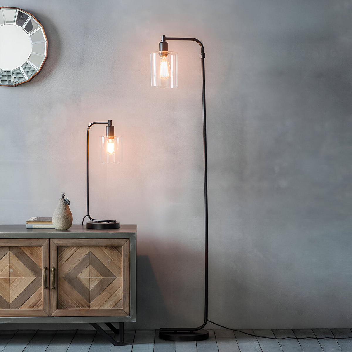 Endon Cranmere table lamp in matt black with clear glass shade and filament bulb on a wooden sideboard, beside a matching black floor lamp.