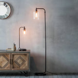 Endon Cranmere table lamp in matt black with clear glass shade and filament bulb on a wooden sideboard, beside a matching black floor lamp.
