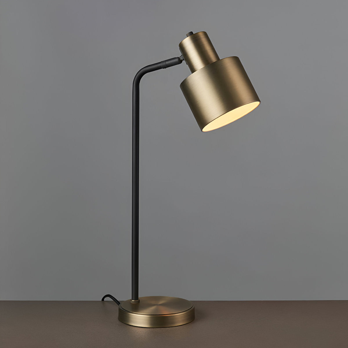 Carlbourne Table Lamp in matt antique brass and black, industrial-style with adjustable cylindrical shade, black stem, and round brass base.