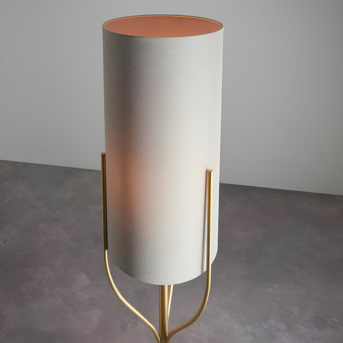 Endon Bramdon floor lamp with tall natural linen cylinder shade and satin brass tripod stem, shown on a plain grey background.