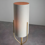 Endon Bramdon floor lamp with tall natural linen cylinder shade and satin brass tripod stem, shown on a plain grey background.