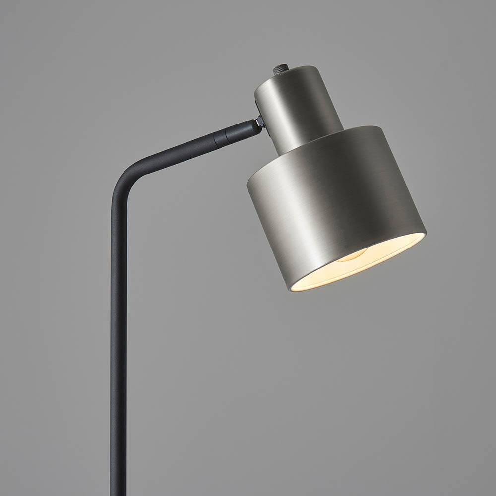 Endon Carlbourne floor lamp head in brushed silver with matt black arm, cylindrical shade and knurled detailing, shown against a plain grey background.