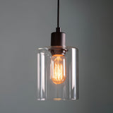 Endon Cranmere pendant light in matt black with a compact clear glass cylinder shade and exposed filament E27 bulb, shown against a grey background.