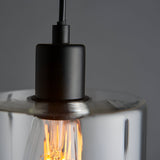 Close-up of the Endon Cranmere pendant light showing the matt black lampholder, black flex, and clear glass shade with a warm filament bulb inside.