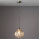 Endon Caldstead pendant light with champagne glass teardrop shade and antique brass fitting on a black flex, shown lit against a grey wall.
