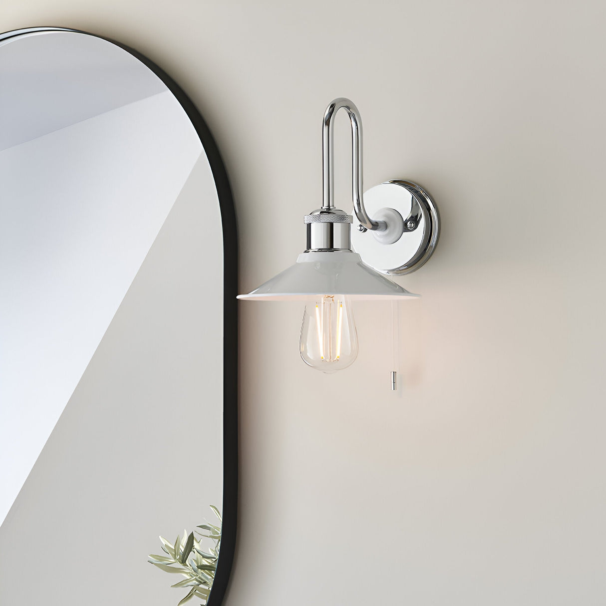 Cardew Bathroom Wall Light in polished chrome with a swan-neck arm, gloss white coolie shade, exposed bulb and pull switch, mounted beside a bathroom mirror.