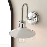 Cardew bathroom wall light with polished chrome swan-neck arm, gloss white coolie shade, pull switch and exposed bulb, mounted on a light wall.