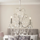 Endon Aldwood 3 light pendant in aged silver with scrolled metal frame and clear faceted crystal droplets, shown above a grey bed.