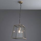 Endon Brenton lantern pendant in brass with tapered metal frame, clear glass panels and filament bulb, suspended from a chain against a grey ceiling.