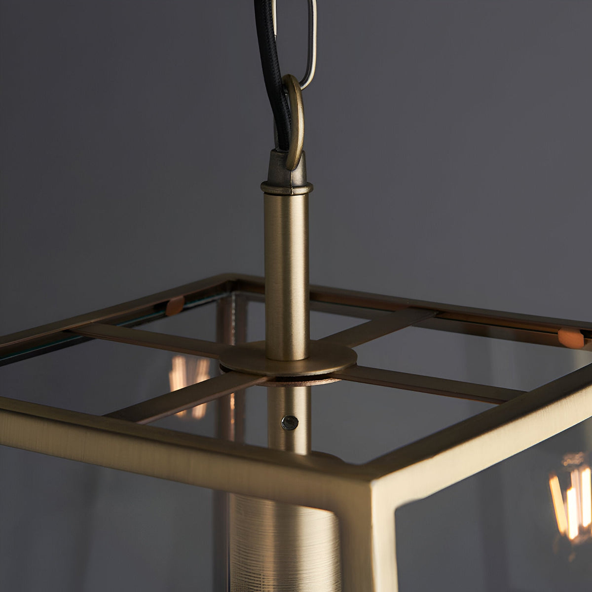 Close-up of Endon Brenton lantern pendant in brass, showing the tapered frame top, clear glass panels, and black fabric flex with loop.