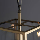 Close-up of Endon Brenton lantern pendant in brass, showing the tapered frame top, clear glass panels, and black fabric flex with loop.