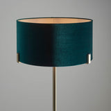 Endon Brendon floor lamp with a green velvet cylinder shade held on slim antique brass metalwork, shown against a plain grey background.