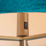 Close-up of the Endon Brendon floor lamp's antique brass lamp holder with rocker switch, beneath a green velvet shade.