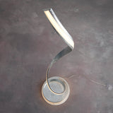 Endon Neve LED floor lamp with a spiralling silver leaf curve and white diffuser, mounted on a round base with in-line cable on a grey floor.