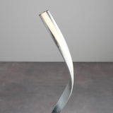 Endon Neve integrated LED floor lamp with a curved silver leaf frame and illuminated white diffuser, shown against a plain light grey background.