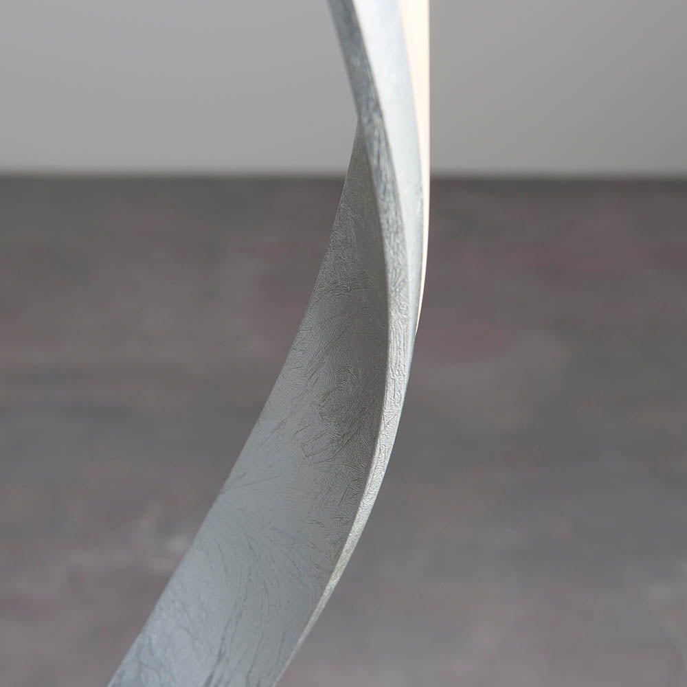 Close-up of the Endon Neve floor lamp base showing the curved silver leaf frame with textured metallic finish against a light grey background.