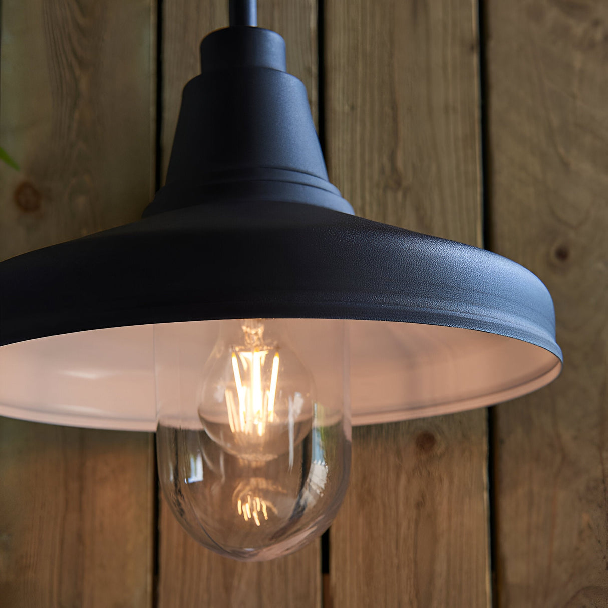 Endon Brackworth outdoor wall light in textured black metal with clear glass shade and E27 filament bulb, mounted against vertical wooden planks.