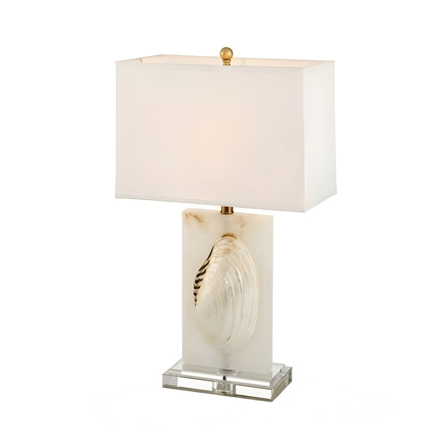 The Carved 1 Light Alabaster Table Lamp – Brass & Soft White features a sculptural shell-inspired base, rectangular white shade, clear platform, and gold finial—bringing elegant decorative lighting to any space.