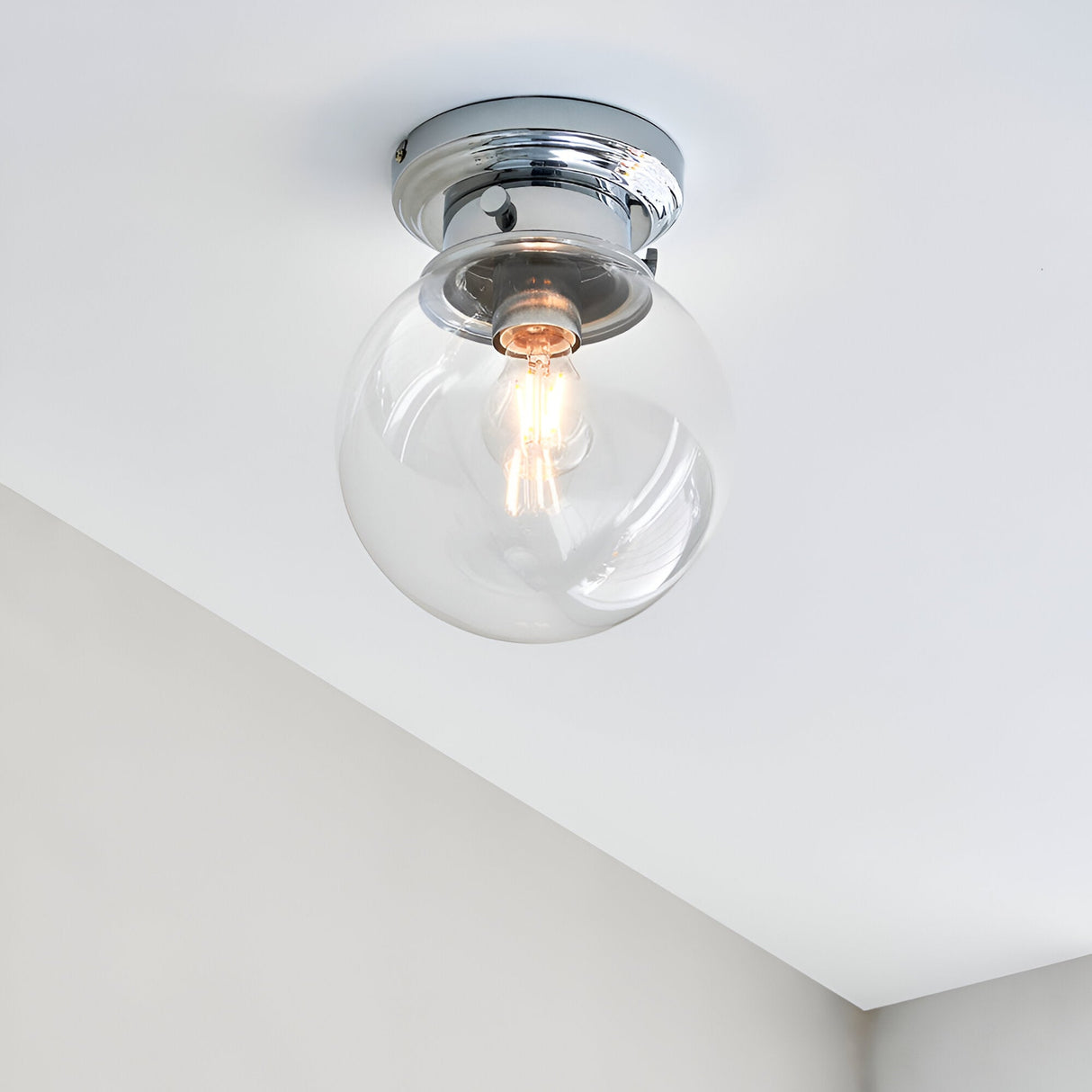Endon Tarn flush bathroom ceiling light in chrome with a clear glass globe shade and single E27 bulb, mounted on a white ceiling.
