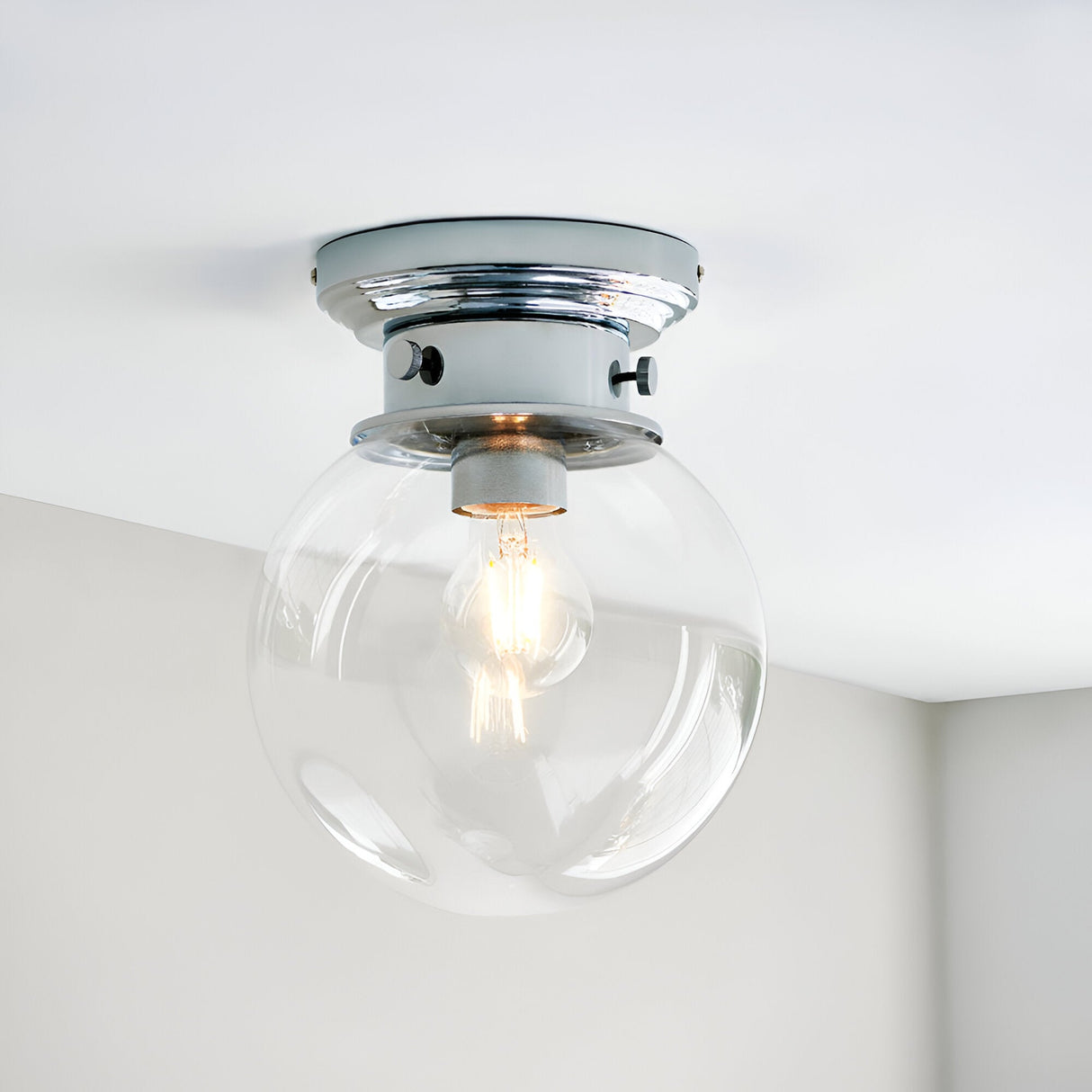 Endon Tarn flush bathroom ceiling light in chrome with a clear glass globe shade and single E27 filament lamp, mounted to a white ceiling.