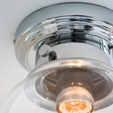 Close-up of the Endon Tarn flush bathroom ceiling light in chrome, showing the polished ring, knurled fixing screws and clear glass shade with lit E27 bulb.