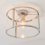Endon Ellery flush ceiling light in brushed nickel, viewed from below with a single E27 bulb inside a clear glass drum shade and metal ring frame.
