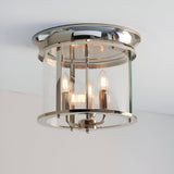 Endon Hollis 3 light flush ceiling light in nickel with cylindrical clear glass shade and three E14 candle lamps, mounted to a white ceiling.