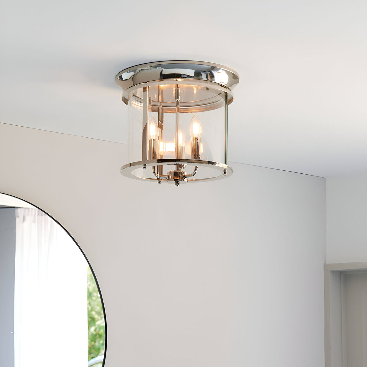 Endon Hollis 3 light flush ceiling light in nickel with cylindrical clear glass shade and three E14 candle lamps, mounted on a white ceiling.