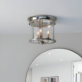 Endon Hollis 3 Light flush ceiling light in nickel with cylindrical clear glass shade and three E14 candle lamps, mounted above a round wall mirror.