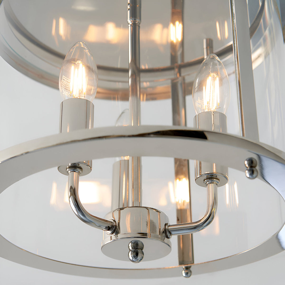 Close-up of the Endon Hollis 3 Light Flush Ceiling Light in nickel, showing lit E14 candle lamps, curved arms and clear glass shade.