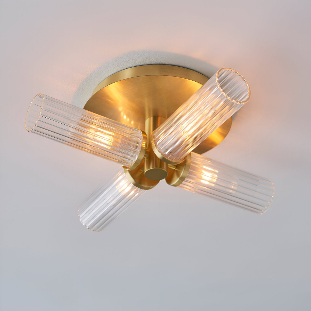 Endon Wren 4 light semi-flush bathroom ceiling light in brass with four ribbed clear glass tube shades on a circular ceiling plate.