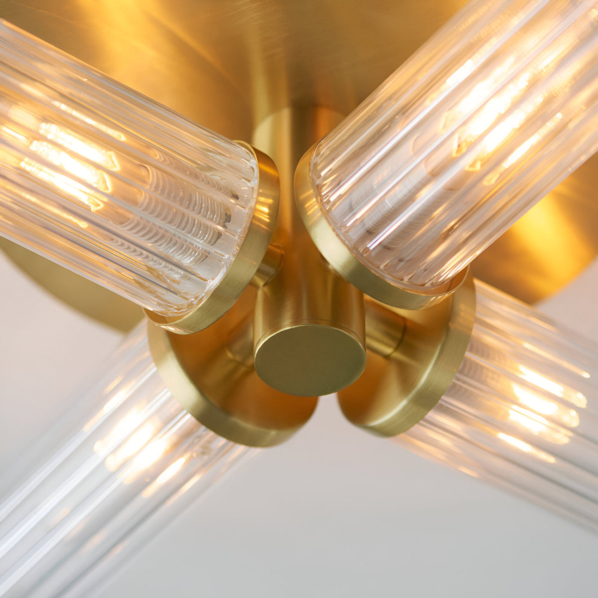 Close-up of Endon Wren 4 Light Semi-Flush Bathroom Ceiling Light in brass, showing four ribbed glass shades on angled arms around a central brass fitting.