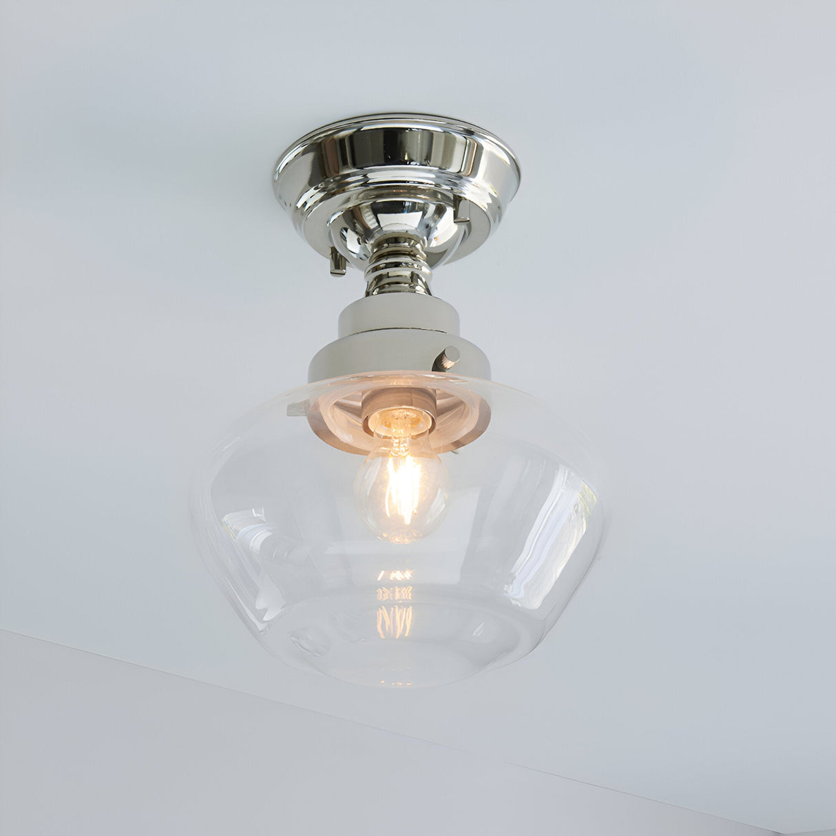 Endon Kedleston semi-flush ceiling light with polished nickel mount and clear glass schoolhouse shade, single E27 bulb lit, mounted on a white ceiling.